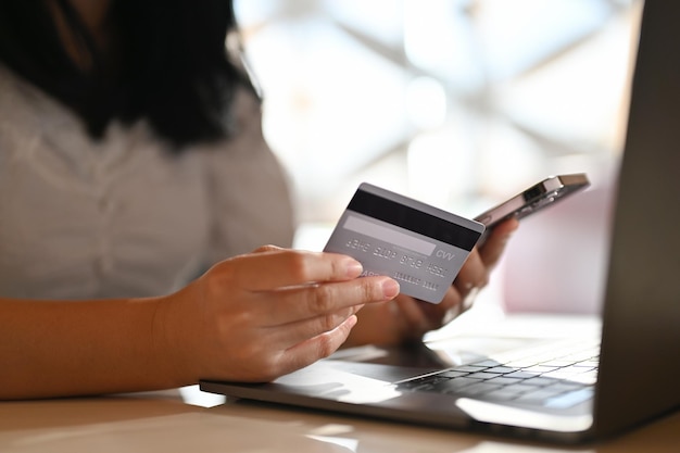 Asian female holding a smartphone and a credit card mobile\
banking credit card payment