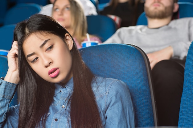 asian female looking away bored sitting at the movie theatre