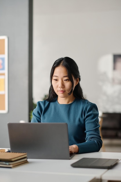 Asian female manager texting on laptop