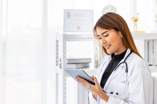 Asian female medical doctor using digital tablet in office clinic hospital with smiling