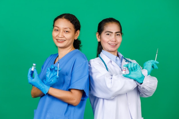 Asian female nurse in scrubs and doctor in white gown holding syringe and Covid 19 vaccine preparing for injection. Concept for Covid 19 vaccination.