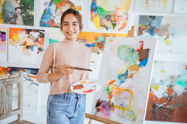 Asian female painter painting on canvas in her workshop