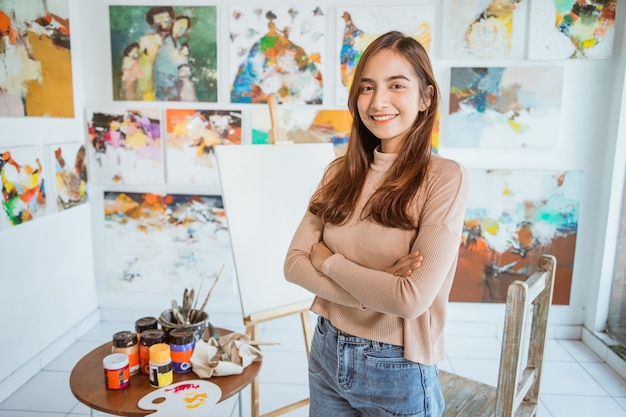 Asian female painter painting on canvas in her workshop