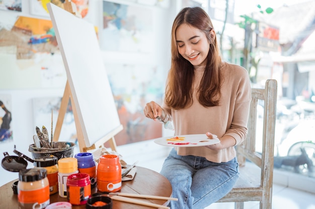 Asian female painter painting on canvas in her workshop