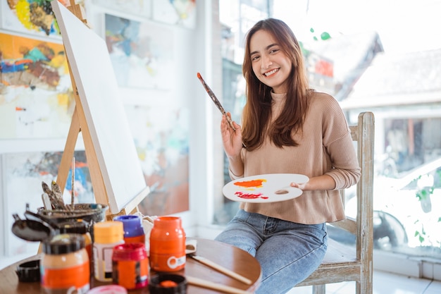 Asian female painter painting on canvas in her workshop