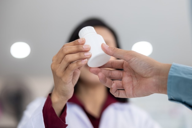 Asian Female pharmacist holding medicine white bottle