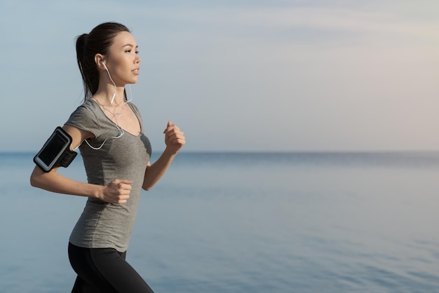 Corridore femminile asiatico che pareggia all'aperto sulla spiaggia