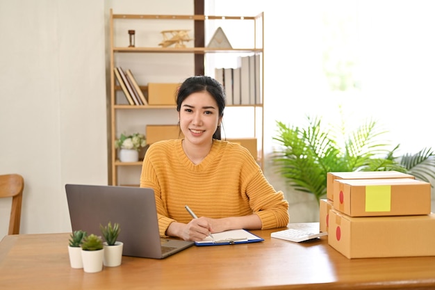 Asian female small online business owner working on her business tasks at her desk