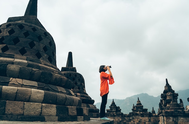 アジアの女性一人旅行者がインドネシア、ジャワのボロブドゥール寺院で写真古代建築物を撮る