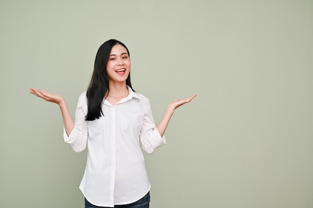 Asian female standing over isolated grey background hands open palm for advertising