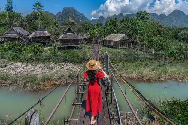 Foto una turista asiatica cammina su un ponte di legno per raggiungere una capanna in mezzo all'acqua