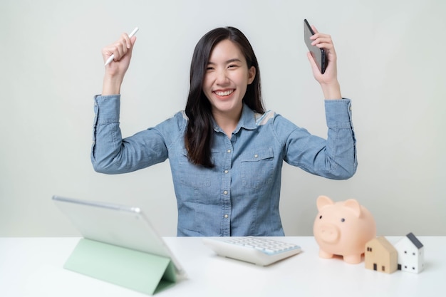 Asian female worker checking income on tablet and saving money