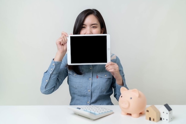 Asian female worker checking income on tablet and saving money