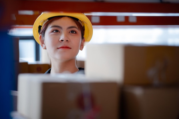 Asian female worker wearing safety clothing is in a warehouse she is checking the goods in the warehouse before shipping The concept of working in the warehouse and working in the warehouse is safe