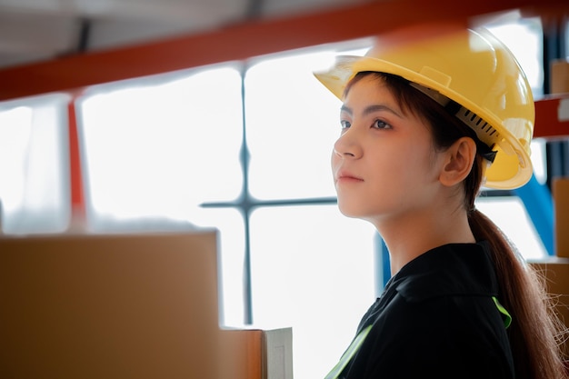 Asian female worker wearing safety clothing is in a warehouse she is checking the goods in the warehouse before shipping The concept of working in the warehouse and working in the warehouse is safe