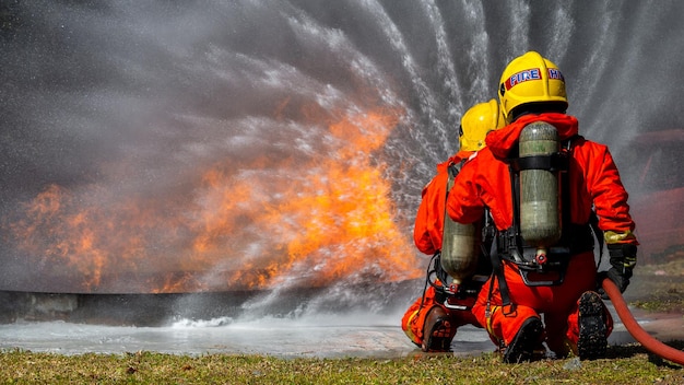 Asian firefighter on duty firefighting Asian fireman spraying high pressure water Fireman in fire fighting equipment uniform spray water from hose for fire fighting