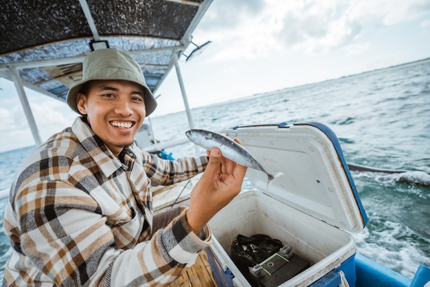 Premium Photo  Asian fisherman smiles as he shows a small fish