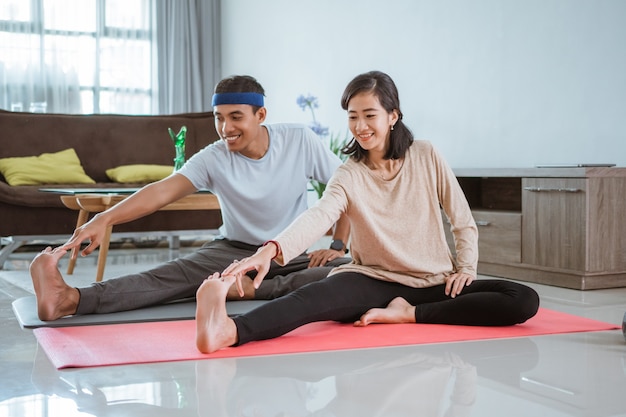 Азиатская фитнес-пара, мужчина и женщина тренируются вместе дома, занимаясь йогой в гостиной
