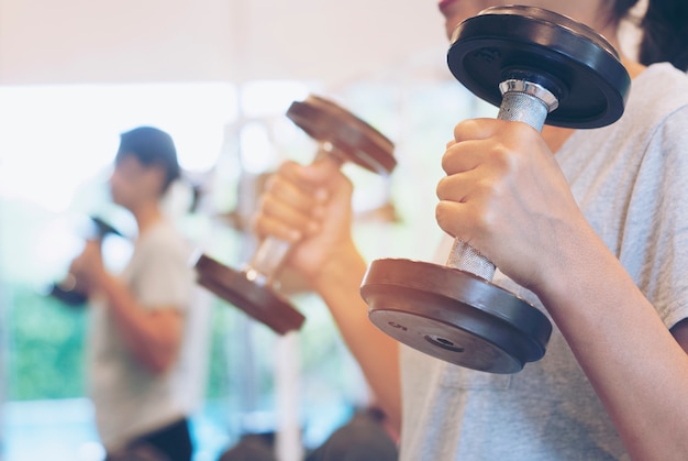 Asian Fitness Woman doing Weight-lifting for Exercise in Gym