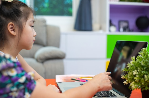 Fmadre asiatica e sua figlia che usano il computer per studiare online insieme in soggiorno