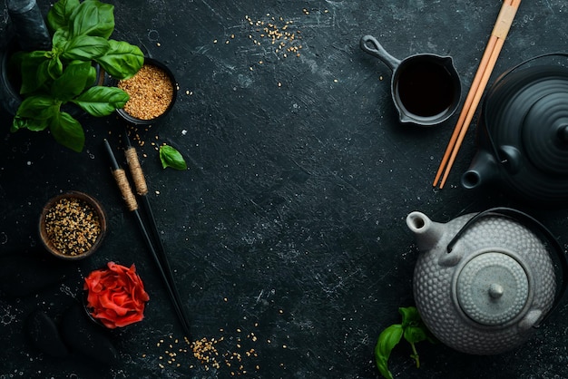 Asian food background: plates, sticks and spices on a black stone background.