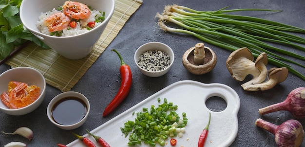 Foto cibo asiatico su sfondo scuro, riso wok con gamberetti e funghi, durante la preparazione, orizzontalmente, ingredienti, messa a fuoco selettiva