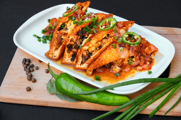 Asian food fried tofu on a plate on a table Green hot chili peppers and green onions