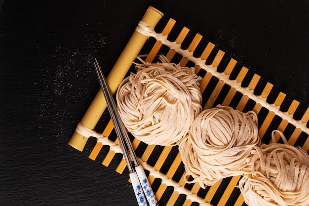 Foto tagliatelle dell'uovo orientali casalinghe dell'alimento asiatico sul vassoio di bambù