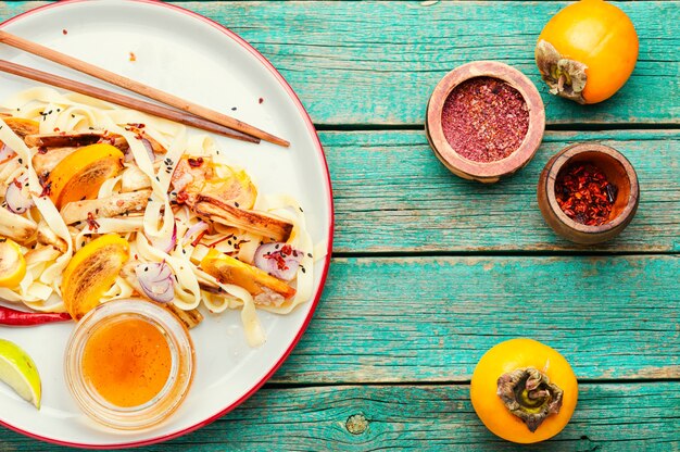 Asian food,salad with noodles, persimmon and eggplant.