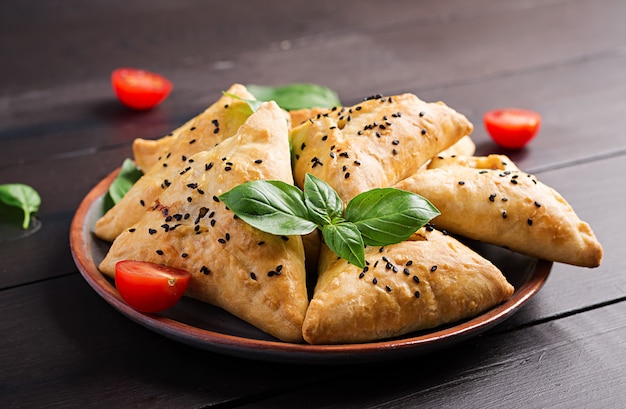 아시아 음식, 닭고기 필렛 및 나무에 녹색 허브와 함께 Samsa (samosa).