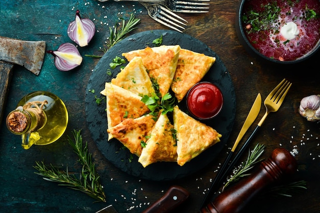 Asian food Samsa with chicken and cheese on a black stone plate with ketchup Rustic style Top view