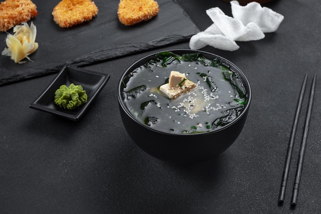 Asian food soup on a black background in a black bowl soup with rice chips top view miso soup with t