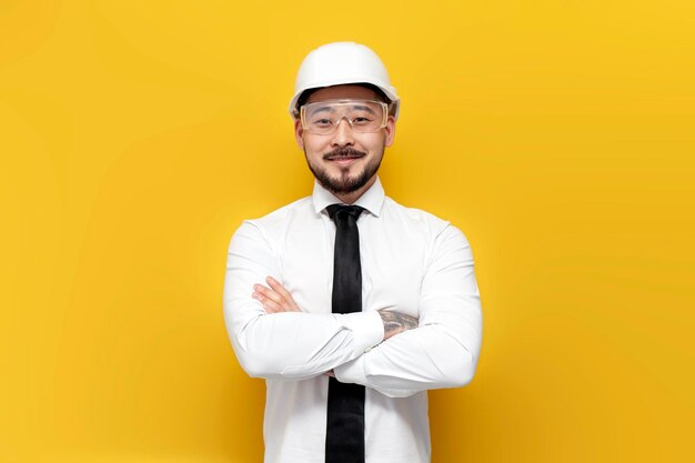 Photo asian foreman in shirt stands with arms crossed on yellow isolated background korean civil engineer