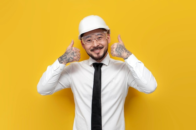 Asian foreman in shirt with tie showing likes over yellow isolated background korean civil engineer