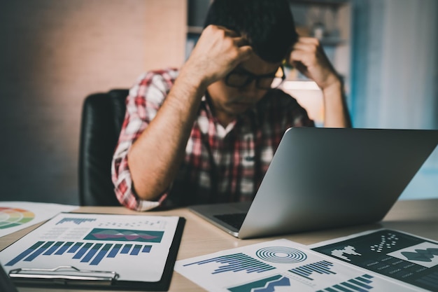 Photo asian freelance man having stressful depression sad time working on laptop home night depression man sad serios working from home man wearing plaid shirt red is rushing work overtime for deadline