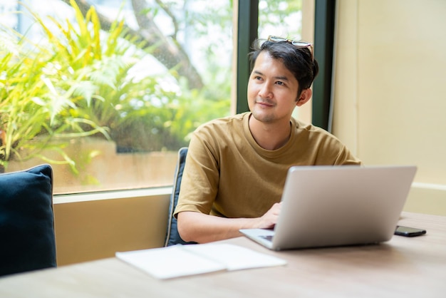 Asian freelance Positive Asian man checking news from network working remotely in public relations area connected to wifi freelance concept