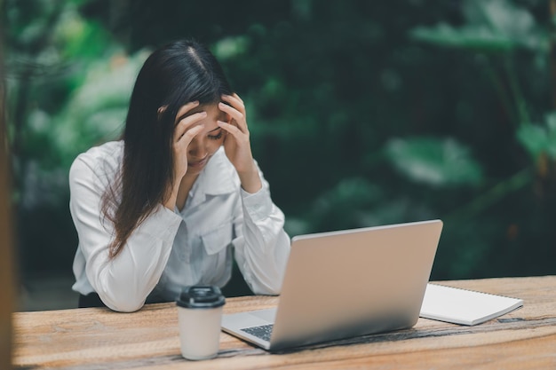 Asian freelance woman hand over head having stressful depression sad time while working on laptop at home Depression woman sad serios working from home Working at anywhere concept