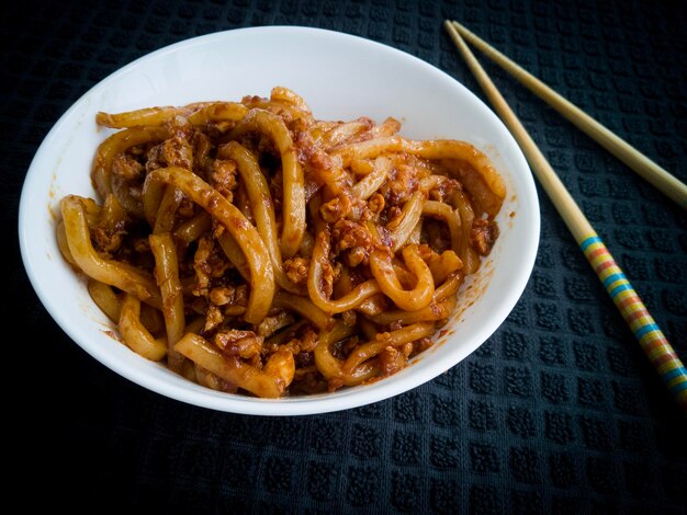 Foto tagliatelle fritte asiatiche con salsa di soia e uova in una ciotola sullo sfondo nero vista in primo piano