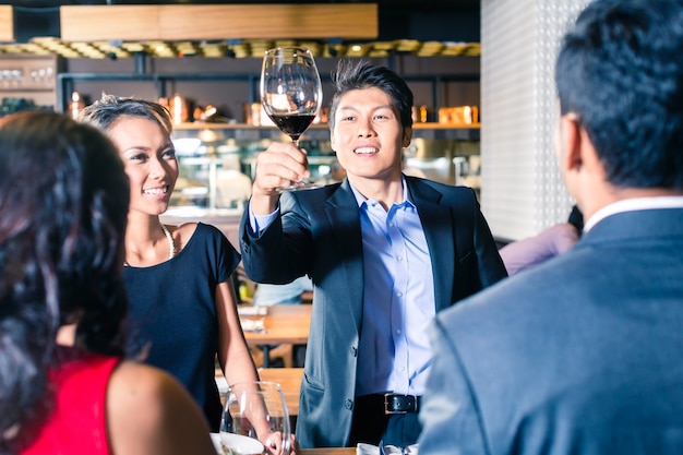 Asian friends toasting with red wine in bar 