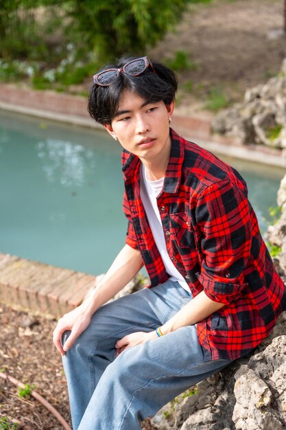 Photo asian gay man sitting next to urban park with water