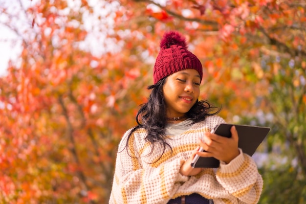 彼女の手の技術コンセプトでタブレットと秋のアジアの女の子