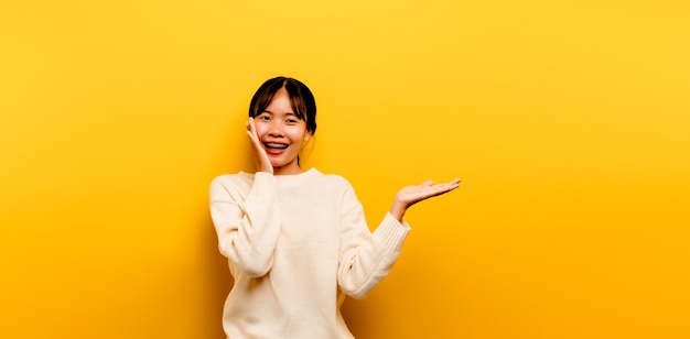 Asian girl Beautiful wearing a white casual dress on a yellow background. Celebrate the victory with