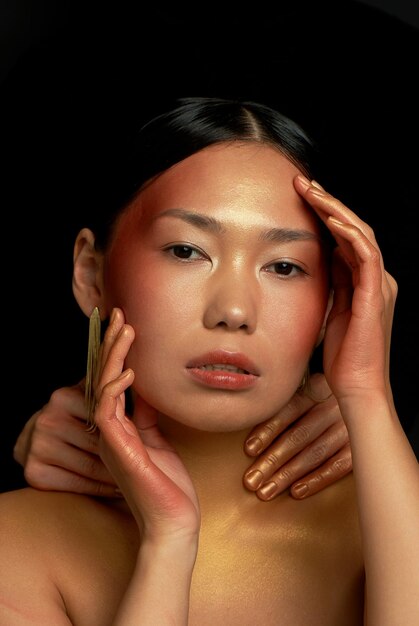 An Asian girl on a black background in the studio Gold Thin collarbones The realm of beauty and perfume Large portrait