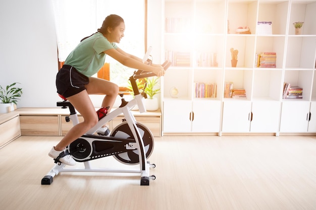 Asian girl cyclist She is exercising in the living room at home