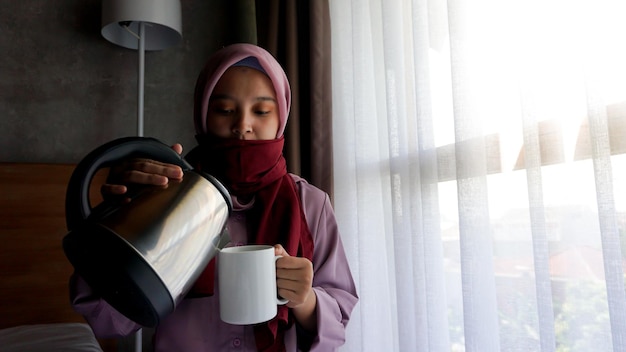 アジアの女の子は寝室で熱い飲み物を飲む