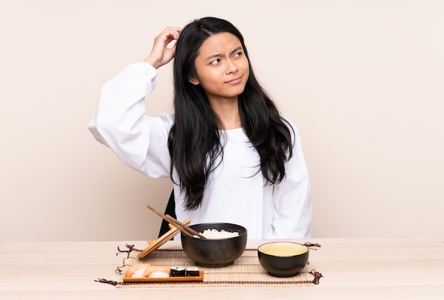 Asian girl eating noodles at a table