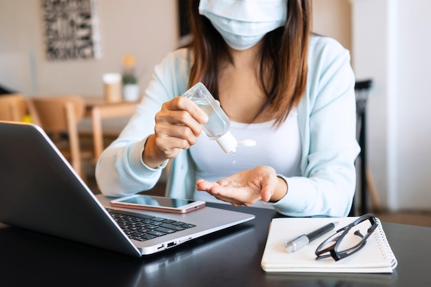 Asian girl in face mask apply hand sanitizer gel onto her hands during the coronavirus crisis Wear a mask in public places and wash your hands to prevent the spread of the COVID19 disease concept