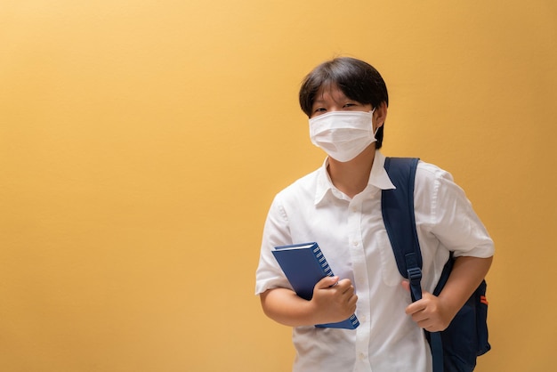 학생복, 교육 개념 및 코로나 바이러스 확산 방지에 학습 장비가 있는 보호 마스크를 착용하는 아시아 소녀.