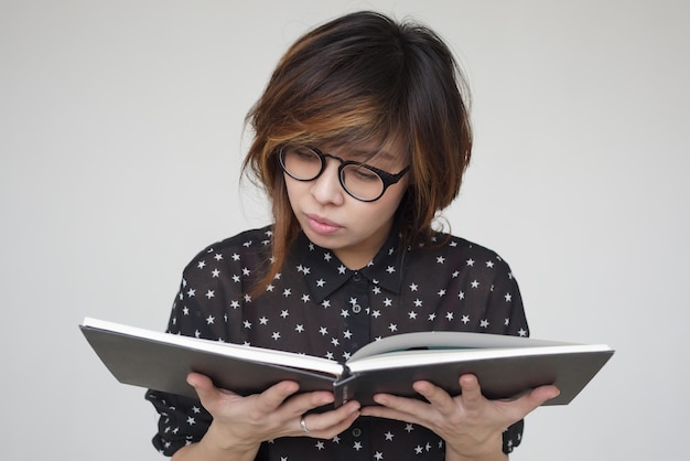 Asian girl in glasses reads the book carefully