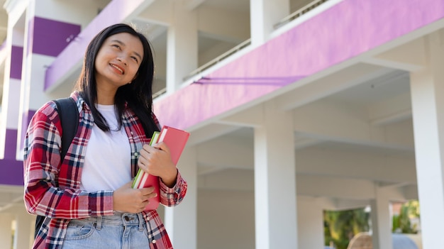 Foto ragazza asiatica con un libro e uno zaino a scuola